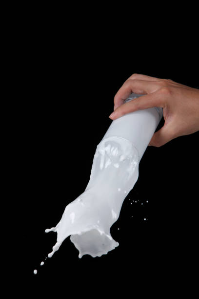 istock hand holding glass milk with the splash isolated on black background 1659174087