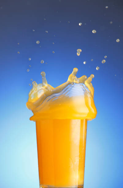 istock orange juice splashing against blue background 1659176633