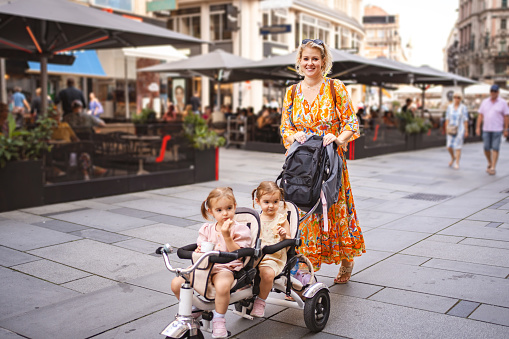 Blonde woman and girl twins in a stroller exploring the city of Vienna
