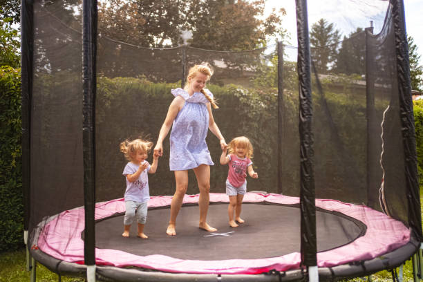 istock Mother and her two daughters jumping on trampoline in their backyard 1659196375