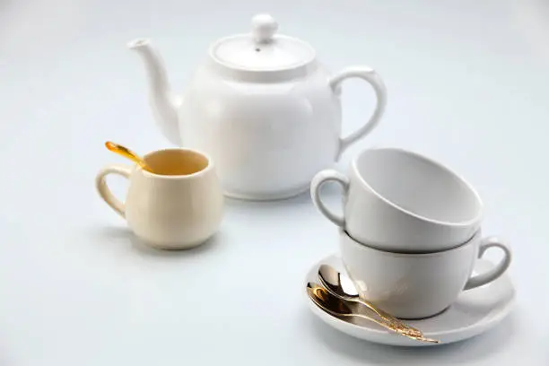Photo of two coffee cups and white teapot
