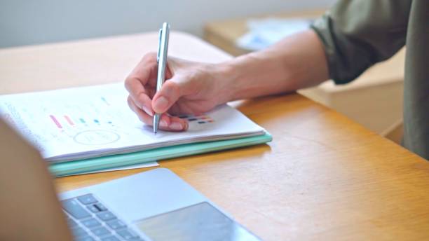 istock Close up hand Young non binary man business worker writing on notebook at office. 1659220539