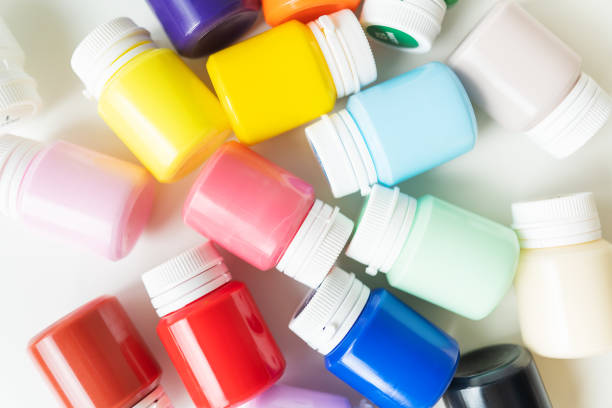 Jars of multi-colored bright acrylic paints isolated on a white background. Close-up, hobby, artist, drawing process