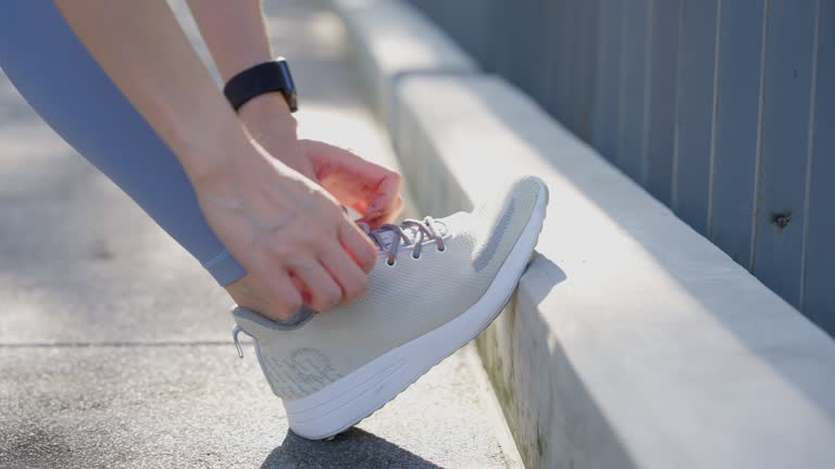 Closeup of female athlete runner tying shoelaces Get ready for a jog in a sunny city park.