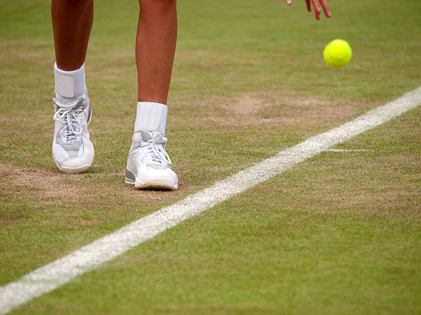 Close-up on a tennis player's feet as they prepare to serve A tennis player bouncing the ball when preparing to serve baseline stock pictures, royalty-free photos & images