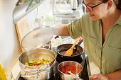 Woman cooking steamed vegetables in a big stainless steel pot