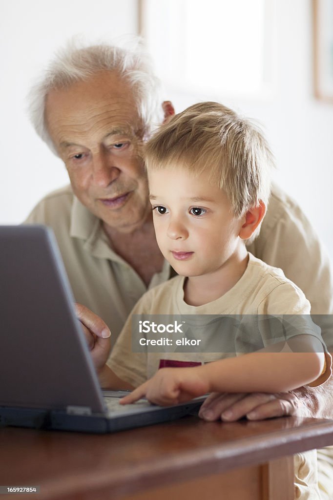 Grand-père et son petit-fils en utilisant un ordinateur portable ensemble peu - Photo de 2-3 ans libre de droits