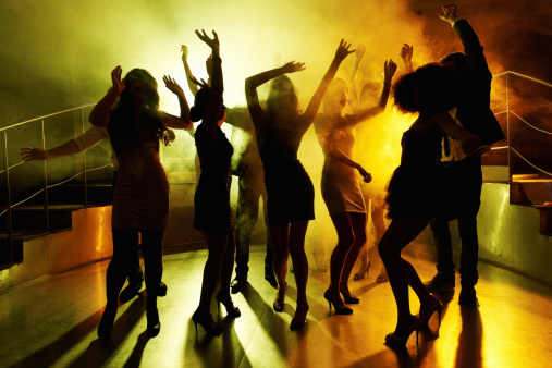 Silhouettes of group of people grooving on the dance floor at a night club