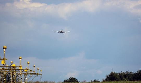 A plane from the side approaching for landing, against the background of clouds. In the foreground, PAPI signal lighting