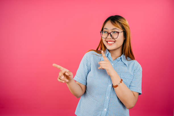 istock Happy Young Woman Pointing While Standing Against A Pink Background 1659306640