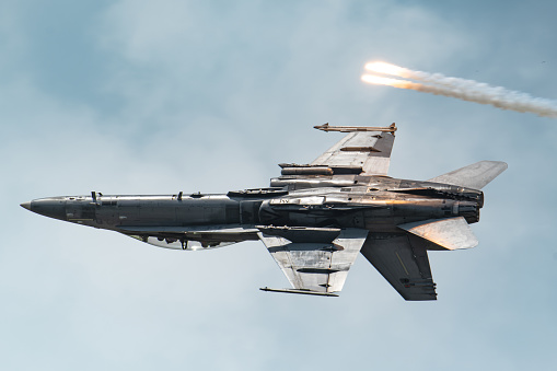 Boeing F/A-18D Hornet flying on its back while releasing flares during an airshow