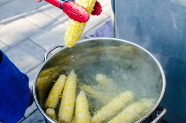 Unrecognizable person removing corncob from boiling water