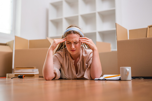 Tired ginger woman with braids lying down on the floor in her new apartment. She is exhausted of moving .