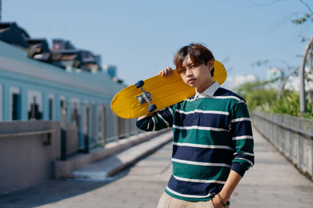 istock Young asian man carrying skateboard on his shoulder 1659367383