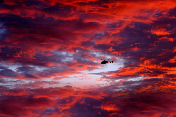 istock Helecopter Flying at Sunset or Sunrise in Sky Dramatic Clouds with Mountains 1659385701
