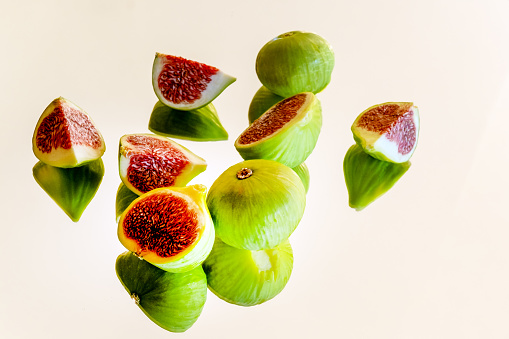ripe figs cut into slices with reflections on a white background