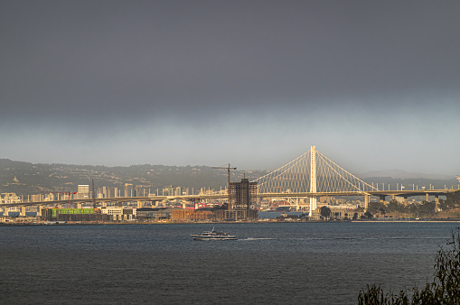 San Francisco, CA, USA - July 12, 2023: From historic Alcatraz island, SF-Oakland Bay bridge and Treasure Island with Oakland and its container terminal on horizon