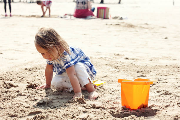 istock Three year old girl making sandcastles on the beach 165942819