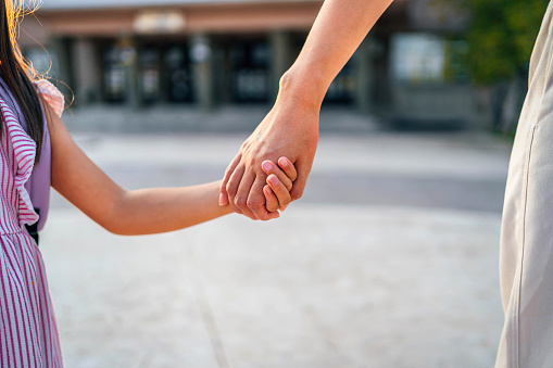 Mother and daughter holding hands while going to school