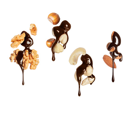 Various nuts covered with melted chocolate close-up isolated on a white background