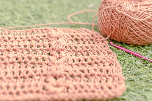 Crochet work on the grass and a yarn