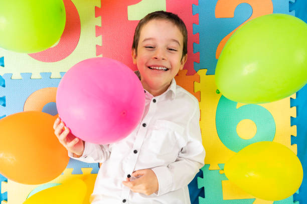 istock smiling boy lying down with multicolored balloons 1659440432
