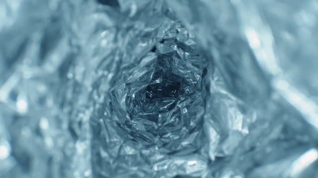Glide dolly inside shot of blue aluminium foil tunnel ice cave imitation, shiny crumpled metal texture