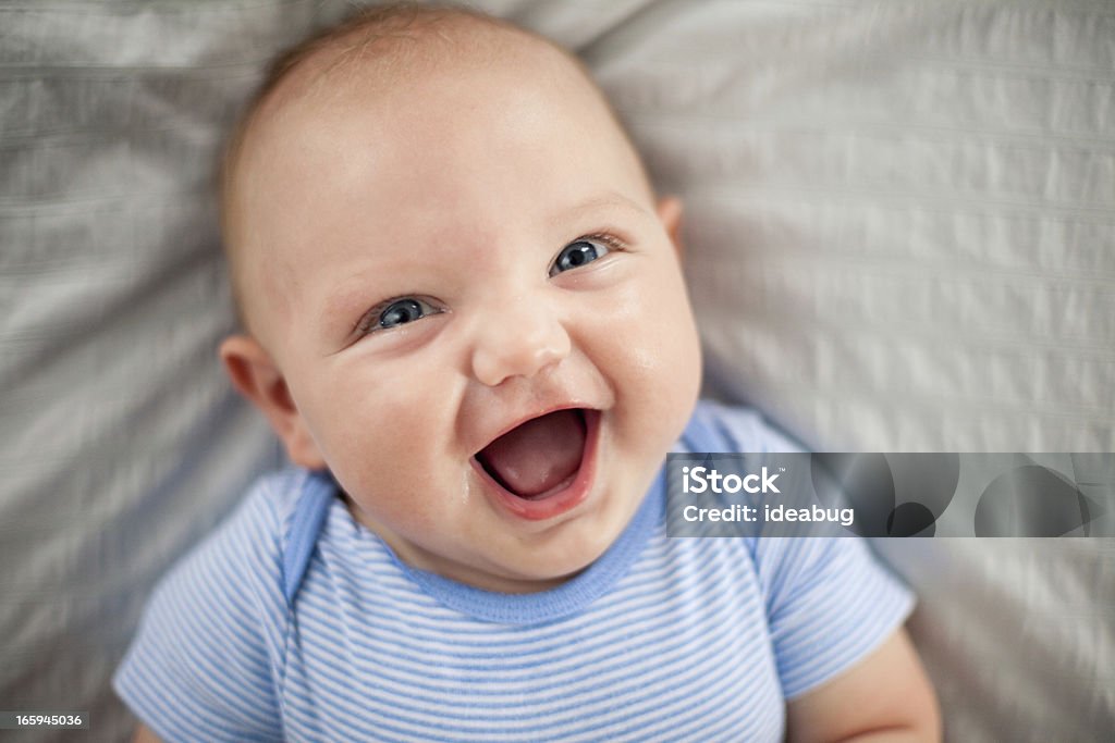 Happy, Laughing Baby Boy Lying on Textured Fabric Color photo of a laughing baby boy lying on his back on a textured blanket. Baby - Human Age Stock Photo