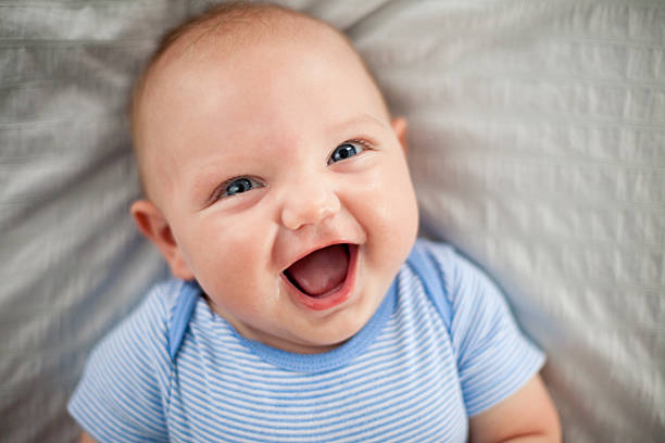 Happy, Laughing Baby Boy Lying on Textured Fabric stock photo