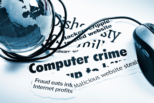 A blue glass globe-shaped paperweight, a computer mouse and cable wrapped round it, rests on print headlines covering  aspects of computer-related crime.