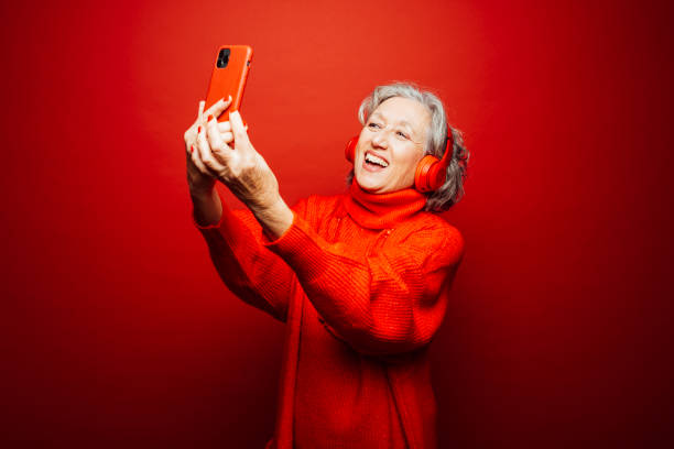 istock Senior woman taking a selfie in front a red background. 1659453435