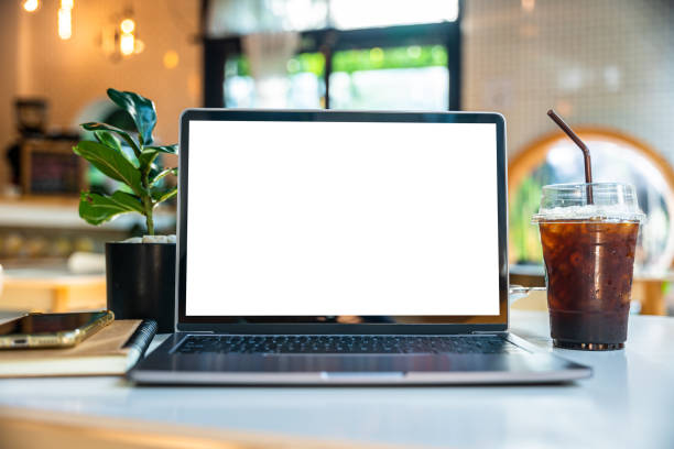 istock Mockup of laptop computer with empty screen with notebook,ice coffee and smartphone on table side the window in the coffee shop at the cafe,White screen 1659454235