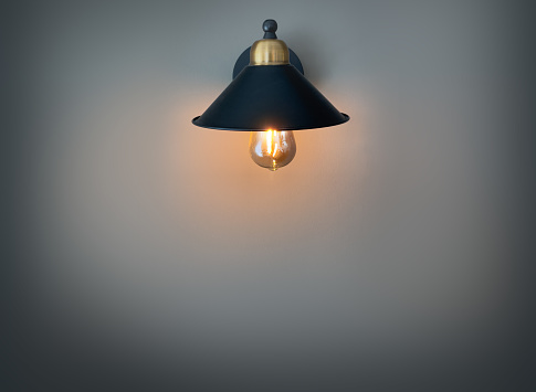 Retro sconce with a light bulb under the shade, hanging on the wall with gray wallpaper Space for copying