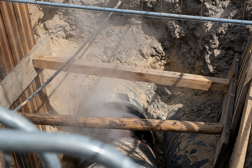 Buried for fixing underground hot water supply lines. Hot steam comes out of the Underground pipe.. water boiling in a tube in the construction site.