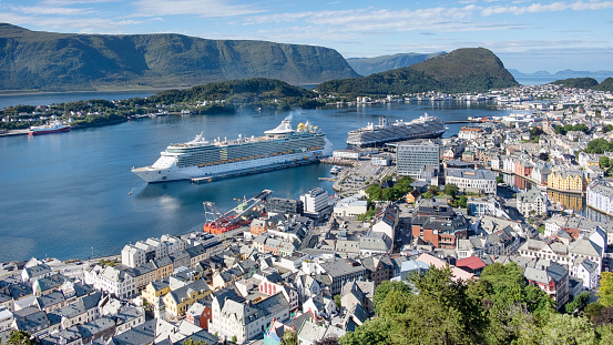 Aksla viewpoint, Alesund, Norway - August 1, 2018: ample views of the town from the vantage lookout, with its distinctive art nouveau architecture, beautiful surrounding nature and cruising tourism.