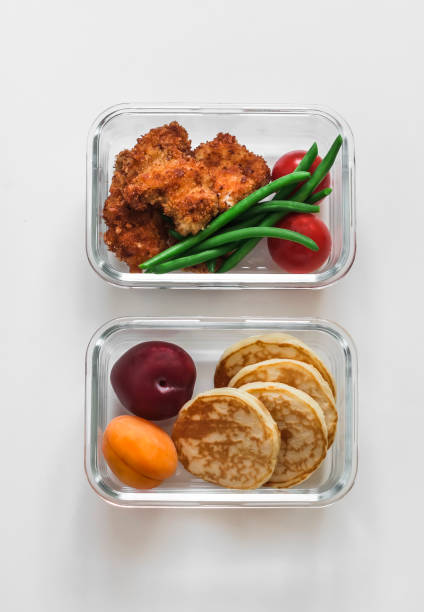istock School lunch box - containers with nuggets, green beans, pancakes and fruit on a light background, top view 1659540992