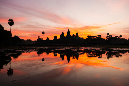 Moody Sunrise and majestic Angkor Wat Temple Panorama backlit from dusk light under beautiful cloudy sky, reflecting in Angkor Wat Pond. Angkor Wat, Siem Reap, Cambodia, Southeast Asia.