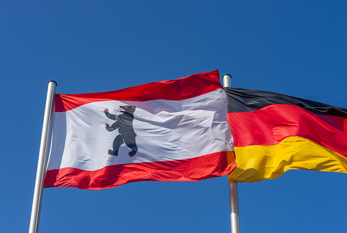 Germany, Berlin, September, 01, 2023 -Low angle view of Berlin and German flags against clear sky