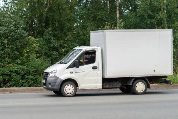 道路上の白い貨物バン - car delivering white mini van ストックフォトと画像