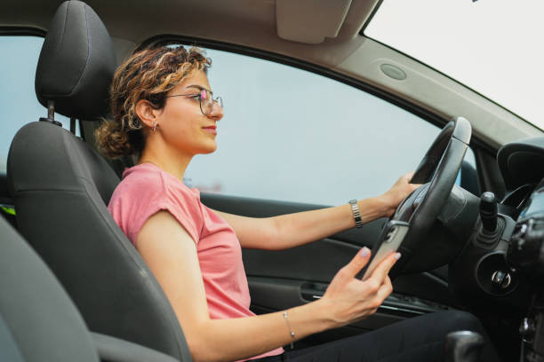 istock young woman looking at her phone while driving 1659663271