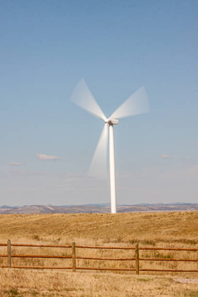 istock Spinning Windmill in a field behind a fence 1659697544
