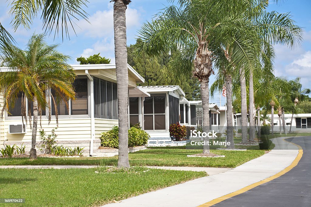 Neat home park full of mobile homes Mobile homes in a row located in a mobile home park in the tropics. Street view with palm trees and sidewalk. Caravan park. Manufactured Housing Stock Photo