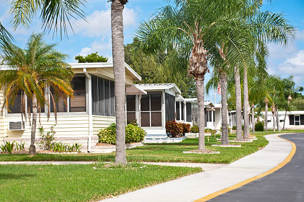 Neat home park full of mobile homes Mobile homes in a row located in a mobile home park in the tropics. Street view with palm trees and sidewalk. Caravan park. florida trailer park stock pictures, royalty-free photos & images