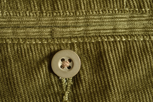detail of a button on green corduroy pants