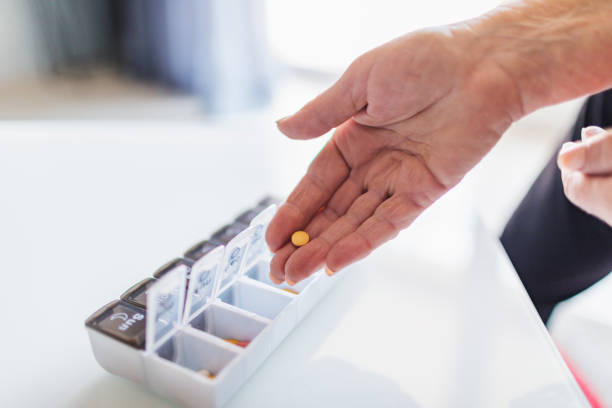 Unrecognisable old woman putting pills in personal pill container for the week