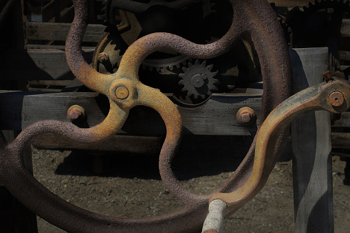 close up of a retail display of a weathered, rusty, old, hand crank attached to a wheel to power agricultural machinery, for sale at a salvage yard, Long Island, New York