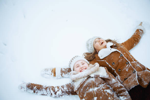 istock smiling modern mother and daughter laying in snow 1659763745