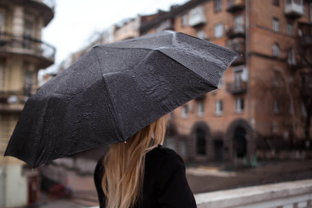 istock unrecognizable woman under black umbrella walking in rainy day. self-absorption, concentration on one's own feelings and emotions concept 1659773914