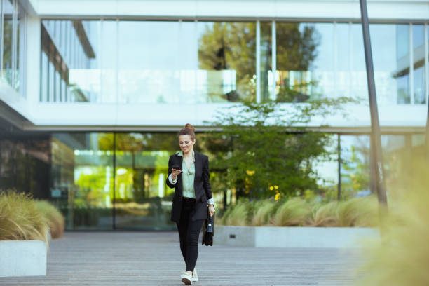 istock female worker in business district using smartphone and walking 1659774996