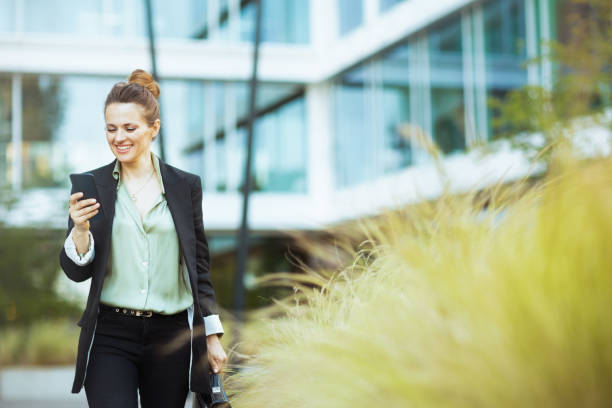 istock female employee in business district using phone and walking 1659775002